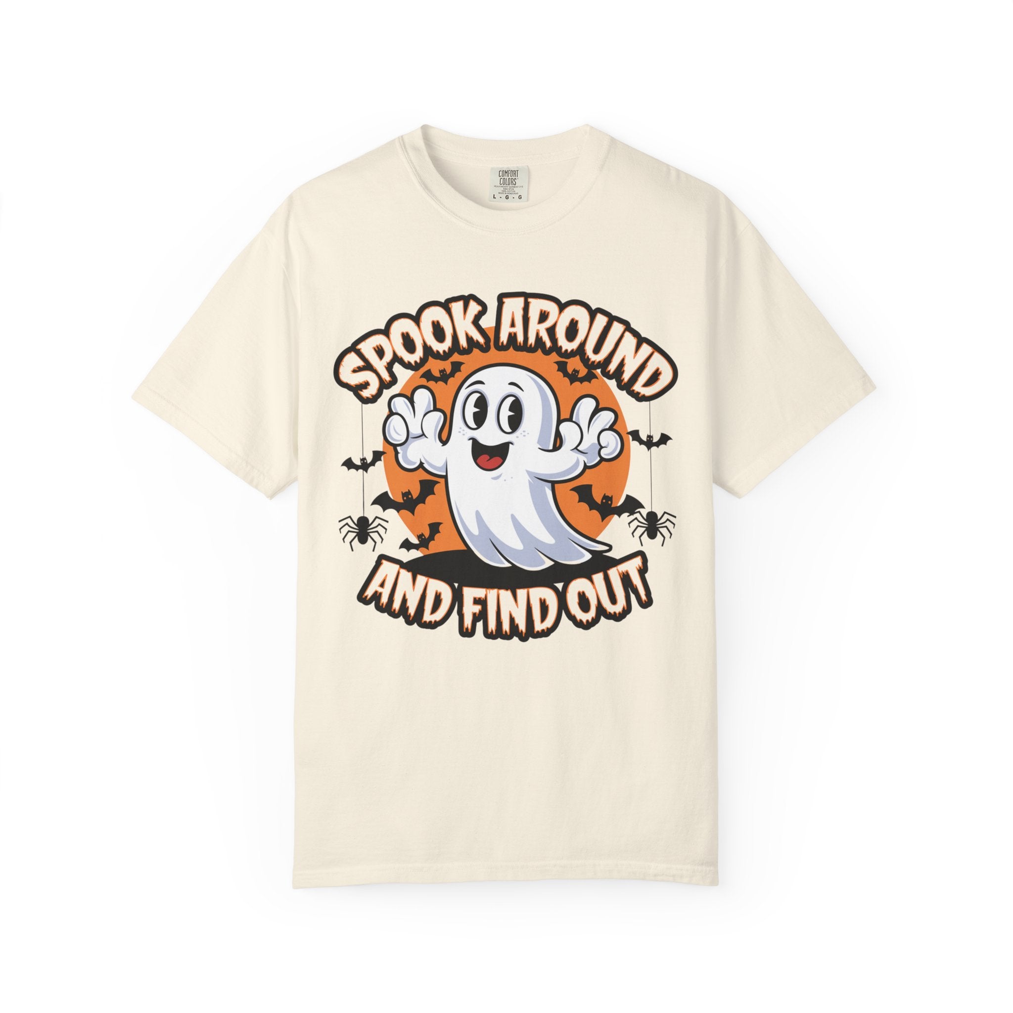 A cream-colored short-sleeve t-shirt with a Halloween graphic on the front. The graphic features a cute white cartoon ghost with outstretched arms, set against an orange circular background with the text 'SPOOK AROUND AND FIND OUT' in a stylized brown font, accented by small black bats and spiders.