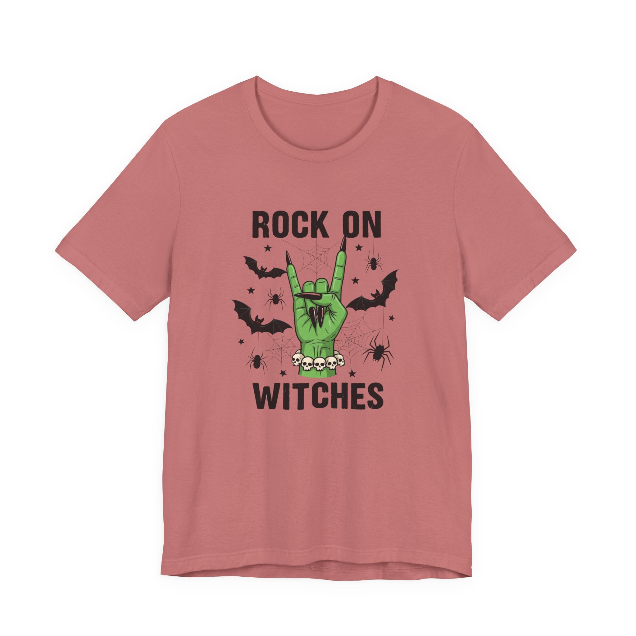 A dusty rose short-sleeve t-shirt with a graphic on the front that reads 'ROCK ON WITCHES' in black text, featuring a green hand making a rock gesture with black bats and spiders.