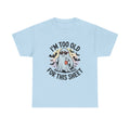 A light blue short-sleeve t-shirt with a graphic of a ghost wearing sunglasses and holding a mug, surrounded by bats and the text 'I'M TOO OLD FOR THIS SHEET'.