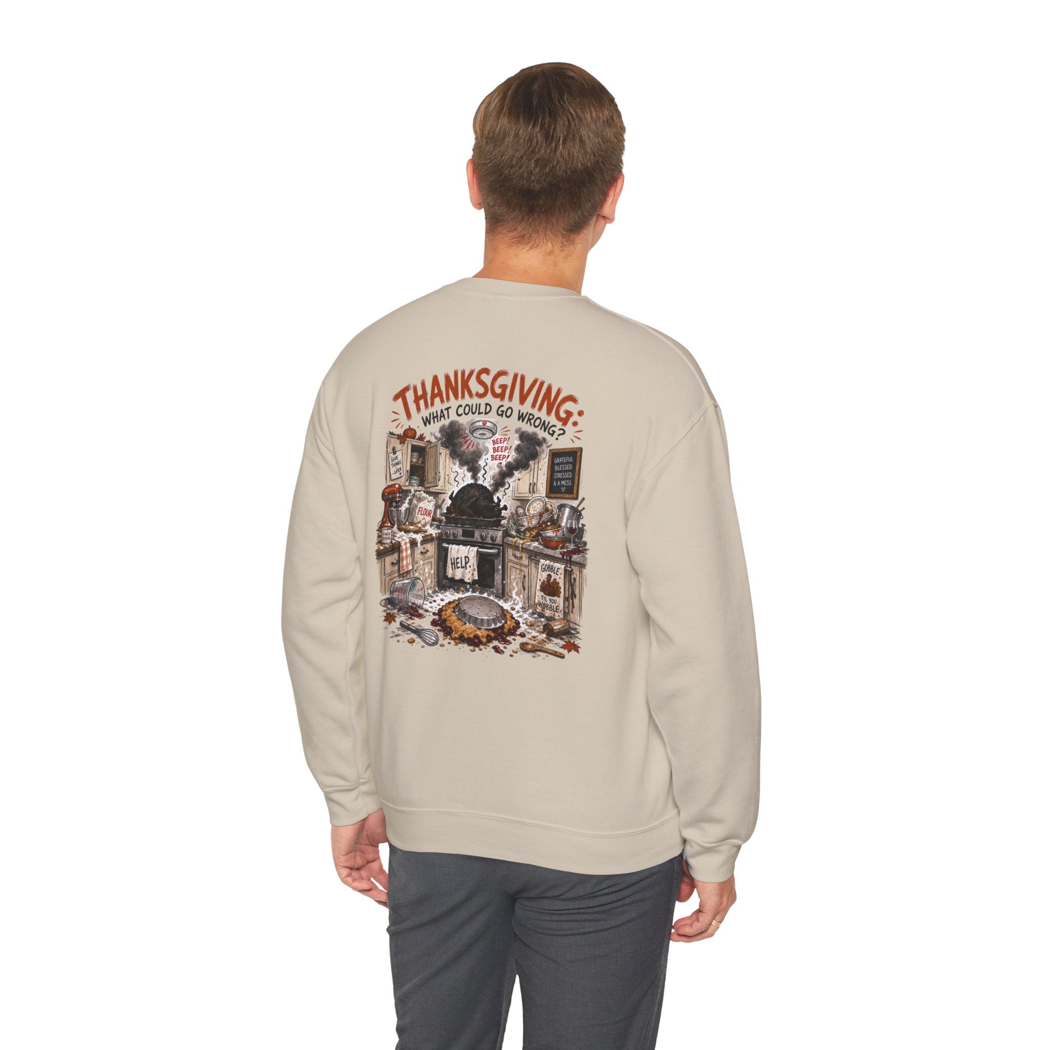 A man viewed from behind wearing a light beige crewneck sweatshirt with a large Thanksgiving-themed graphic print on the back, paired with dark gray pants, against a plain white background.
