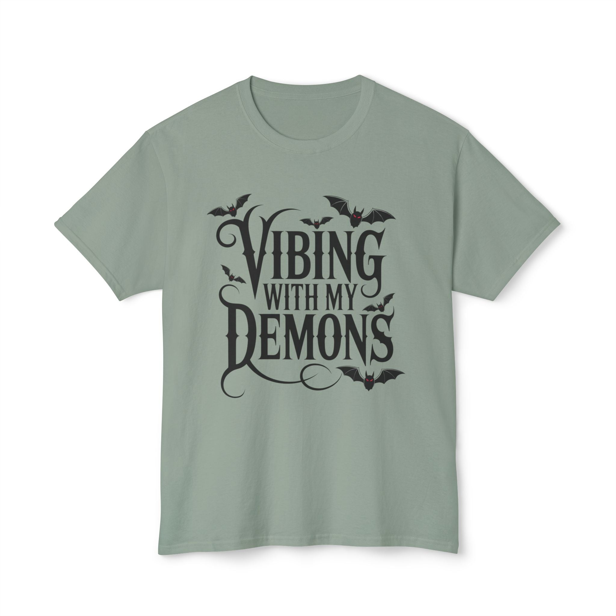 A sage green crewneck t-shirt with a black graphic print that reads 'Vibing with my demons' accompanied by bat silhouettes, displayed on a clean white background.