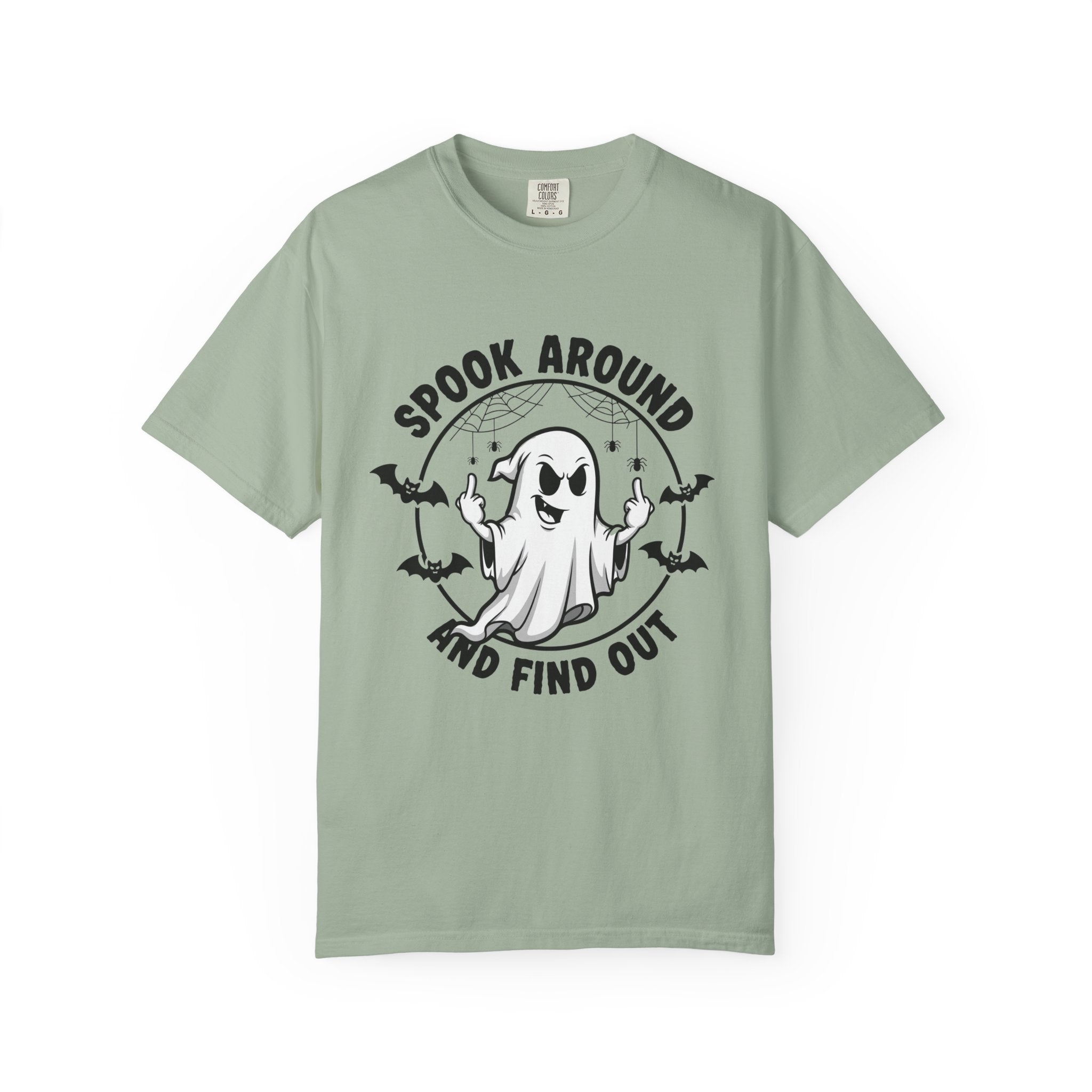 A sage green short-sleeve t-shirt with a black and white graphic of a cartoon ghost surrounded by bats and the text 'SPOOK AROUND AND FIND OUT'.