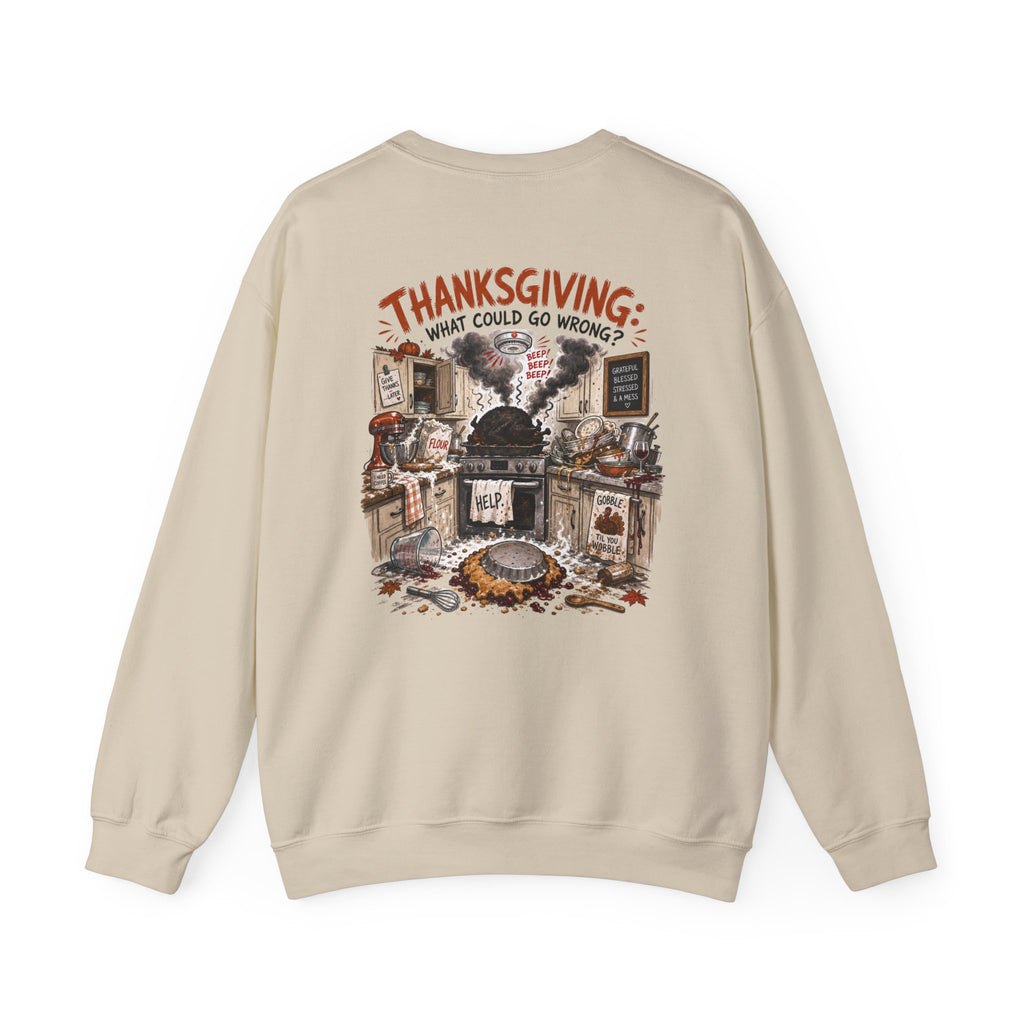 A beige crewneck sweatshirt shown from the back, featuring a detailed graphic illustration of a chaotic Thanksgiving dinner scene with the text 'THANKSGIVING: WHAT COULD GO WRONG?' printed in red and black.