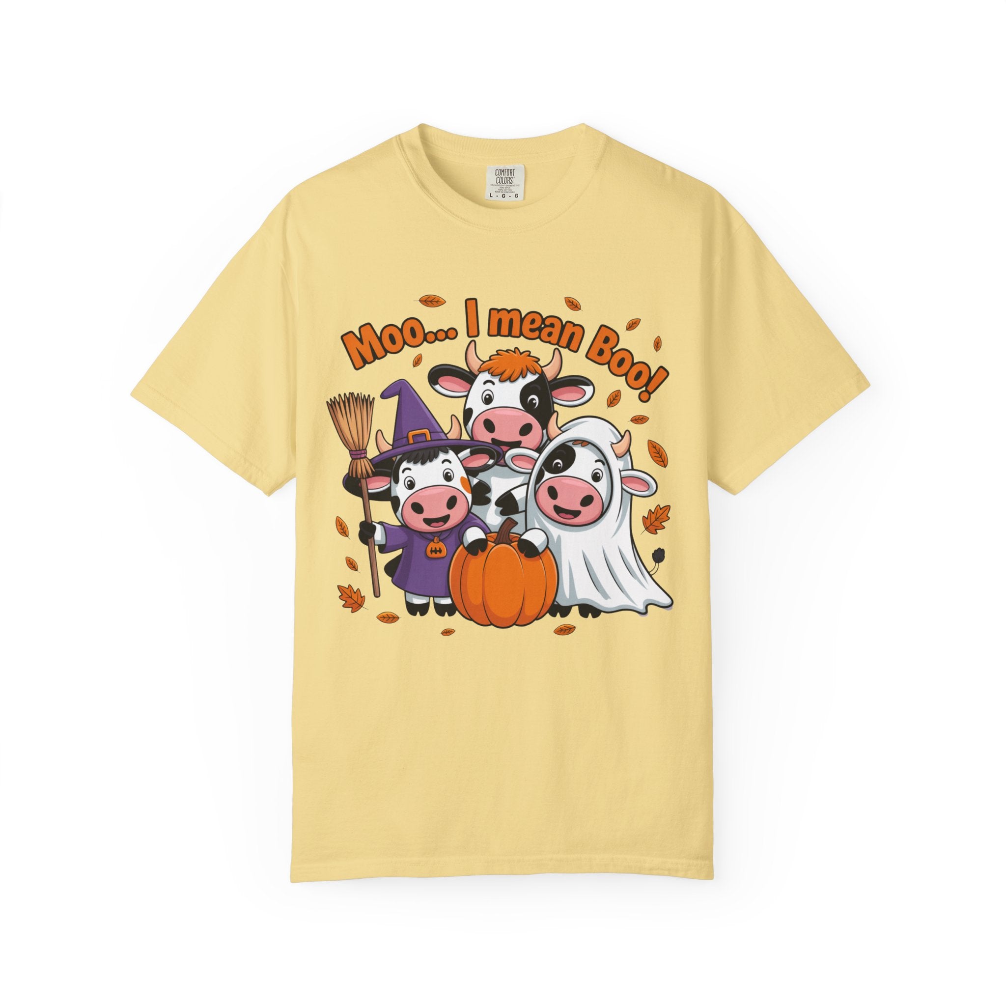 A pale yellow short-sleeve crewneck t-shirt featuring a cartoon graphic of three cows in Halloween costumes (witch, pumpkin boy, and ghost) with the text 'Moo.