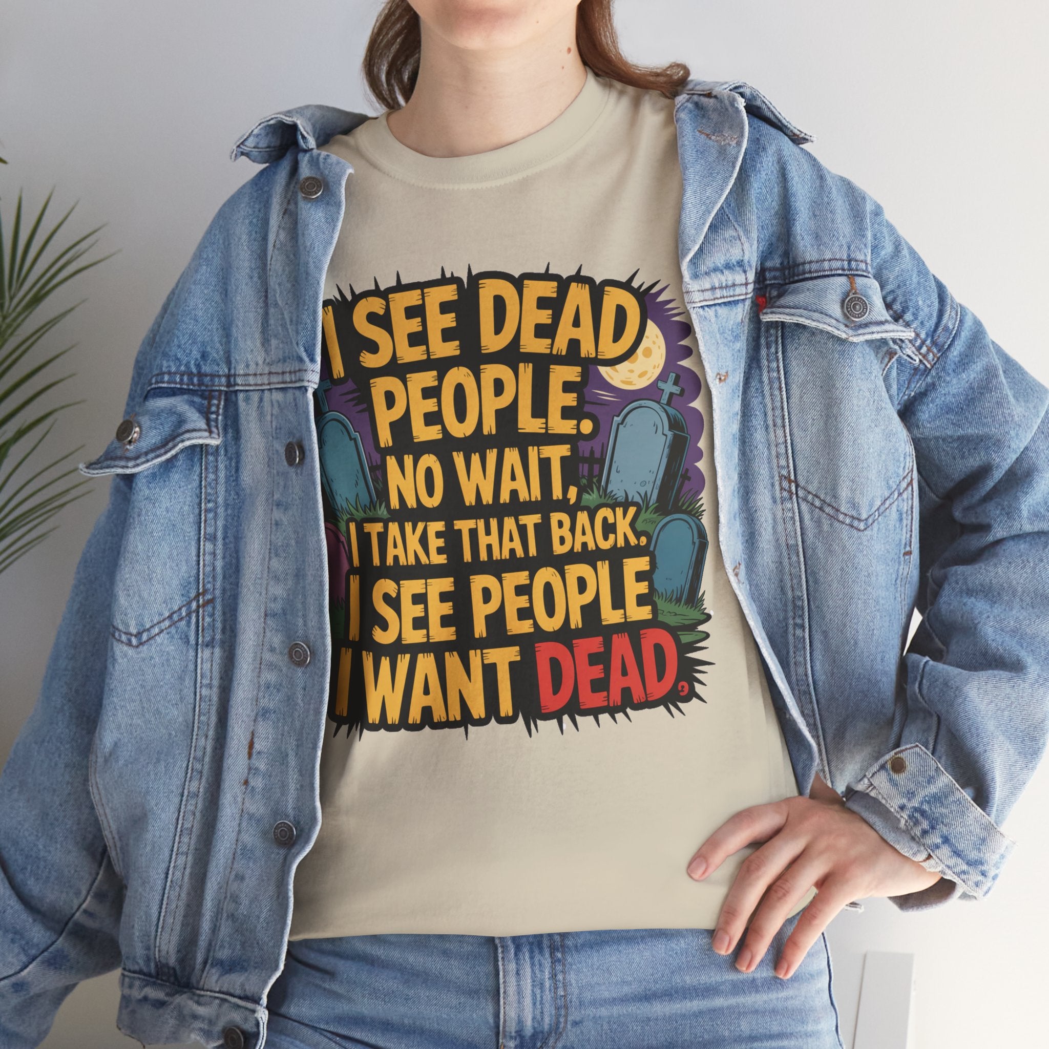 A person wearing a beige graphic t-shirt under an open light-wash denim jacket. The t-shirt features a bold graphic with the text 'I SEE DEAD PEOPLE.