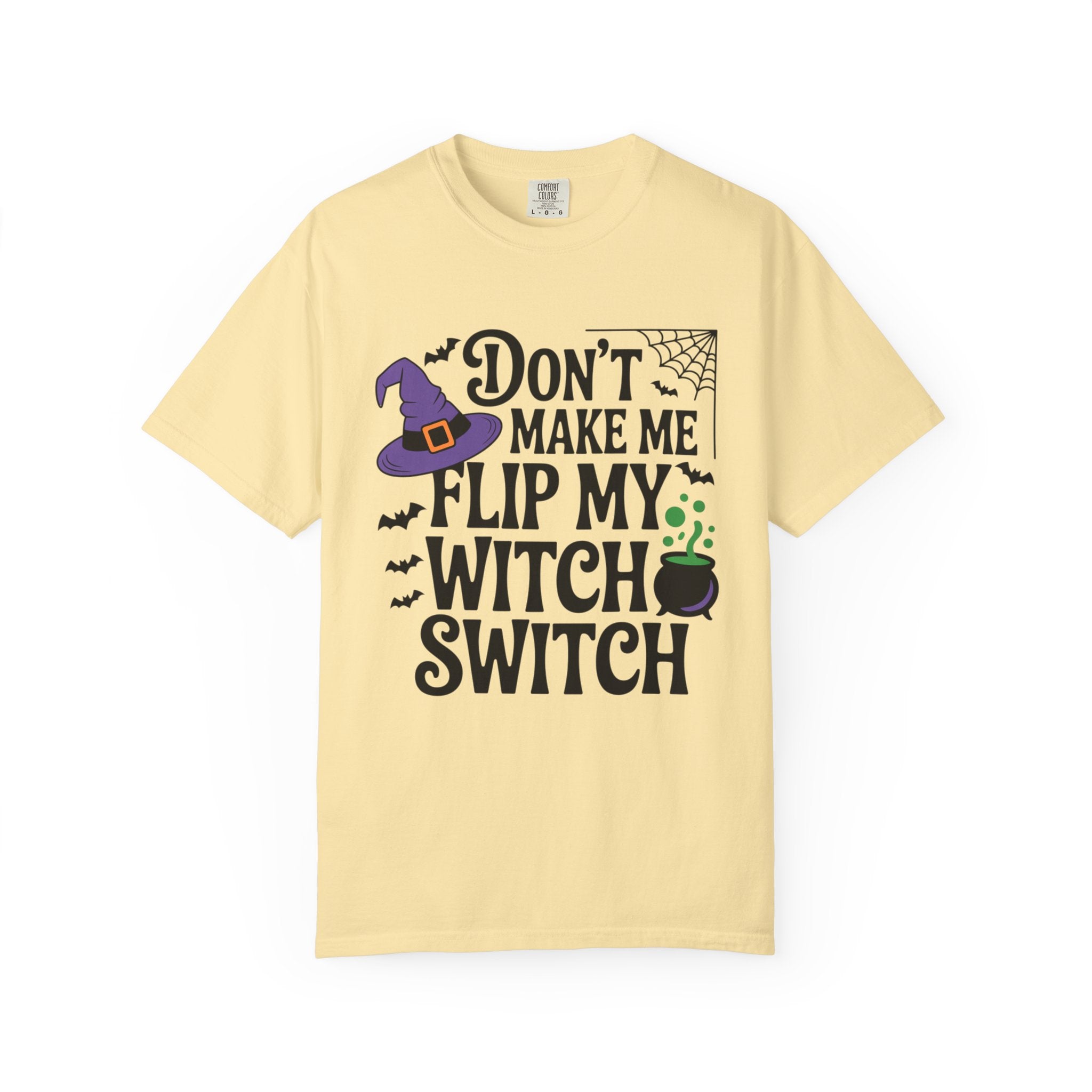 A pale yellow short-sleeve t-shirt with a Halloween-themed graphic print that reads 'DON'T MAKE ME FLIP MY WITCH SWITCH' in black text, accompanied by a purple witch hat, spiderweb, bats, and a cauldron.