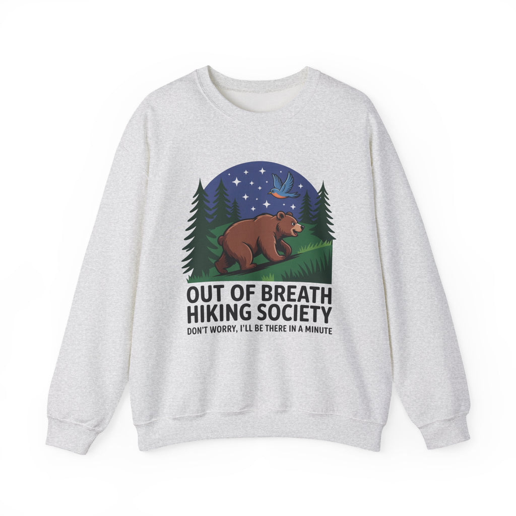 A light heather gray crewneck sweatshirt featuring a graphic print of a brown bear under a starry night sky with pine trees, and the text 'OUT OF BREATH HIKING SOCIETY' and 'DON'T WORRY, I'LL BE THERE IN A MINUTE'.