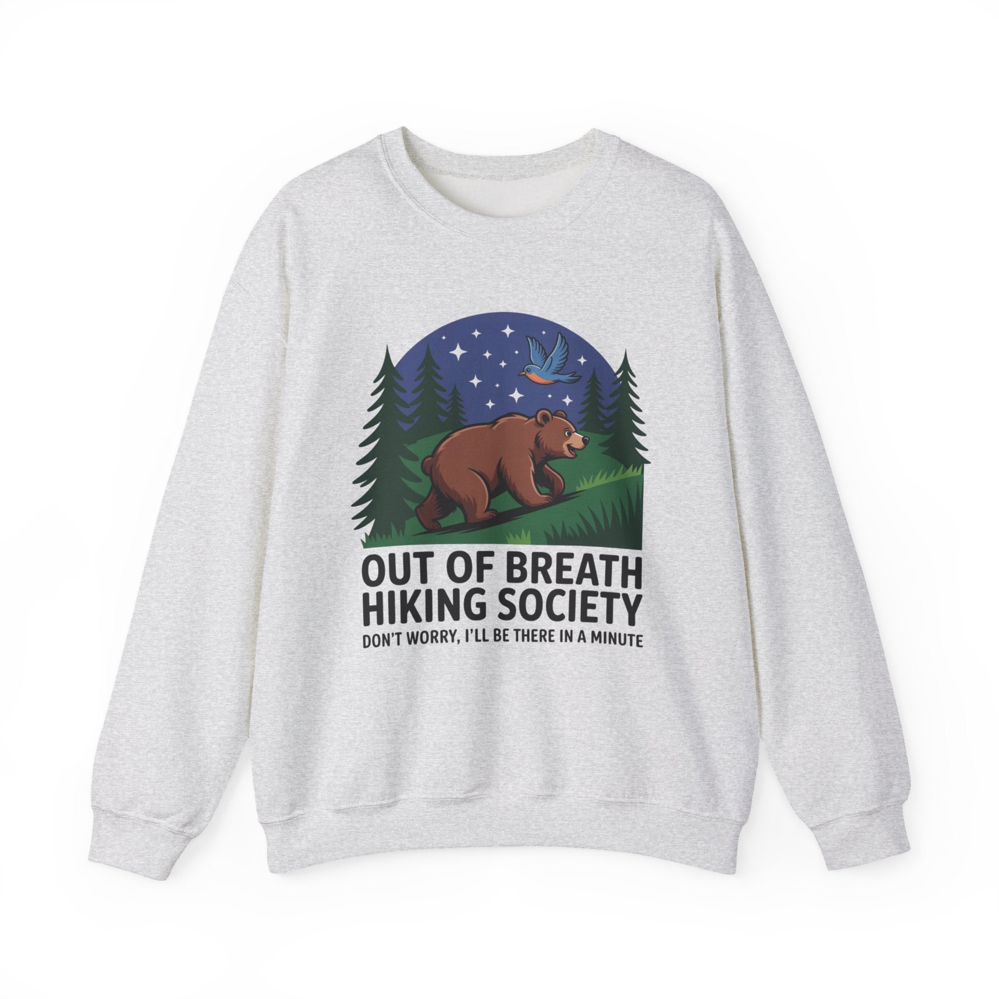 A light heather gray crewneck sweatshirt featuring a graphic print of a brown bear under a starry night sky with pine trees, and the text 'OUT OF BREATH HIKING SOCIETY' and 'DON'T WORRY, I'LL BE THERE IN A MINUTE'.