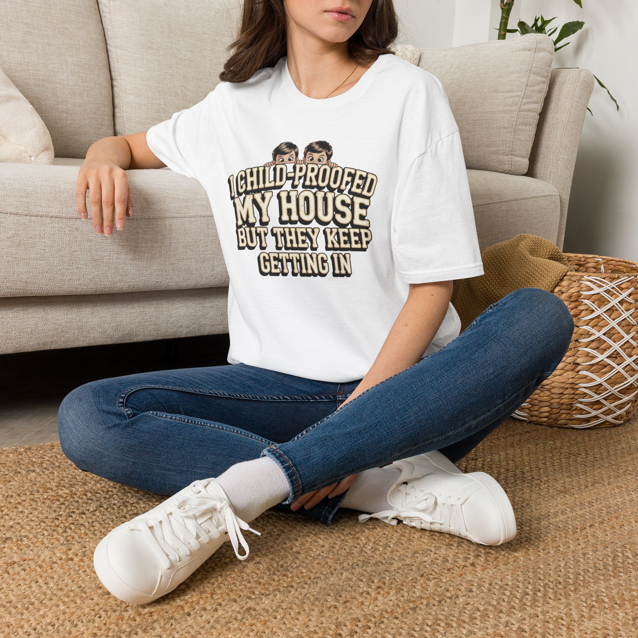 Person wearing a white t-shirt with a graphic design of a dog and text, sitting on a couch.