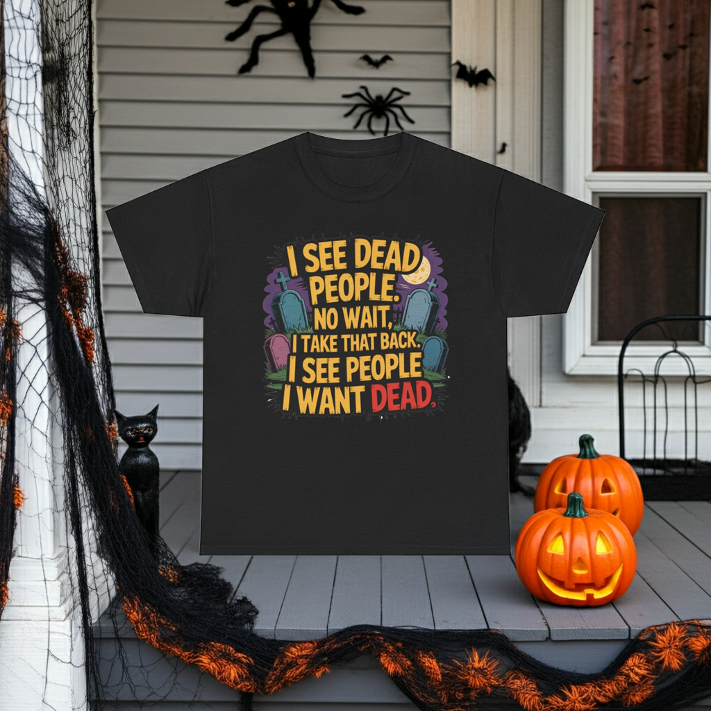 A black graphic t-shirt displayed on a decorated Halloween porch. The shirt features a colorful graphic with tombstones and the text 'I SEE DEAD PEOPLE, NO WAIT, I TAKE THAT BACK, I SEE PEOPLE I WANT DEAD'.